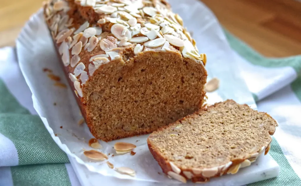 Sliced banana bread loaf topped with flaked almonds