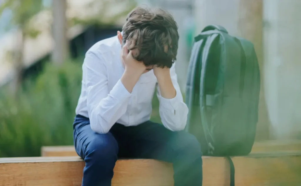 Stressed man sitting with head in hands outdoors