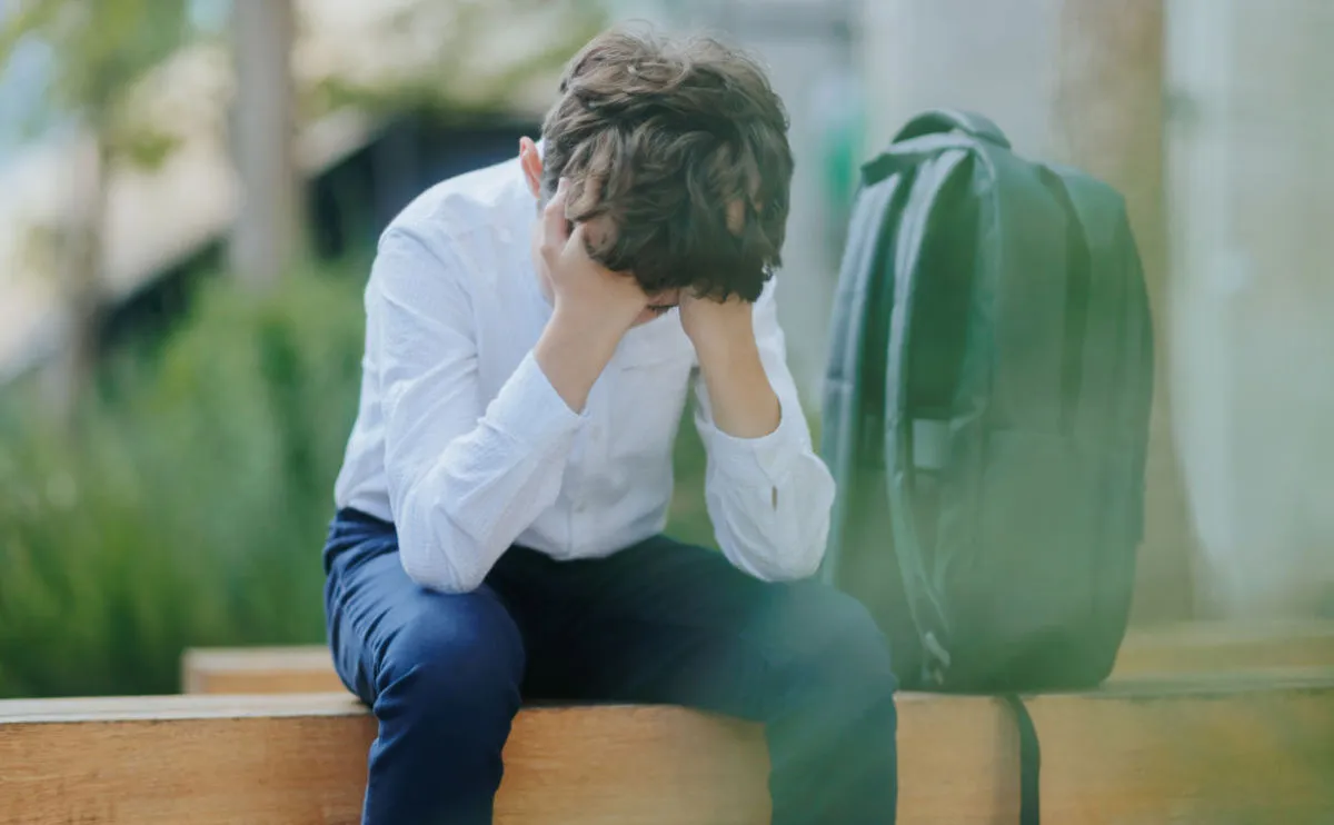 Stressed man sitting with head in hands outdoors