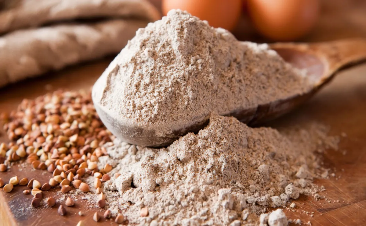 Buckwheat flour overflowing on wooden spoon