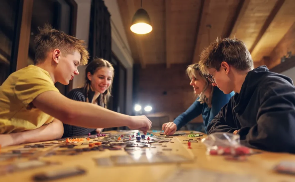 Four young people playing a board game together indoors. No screens!