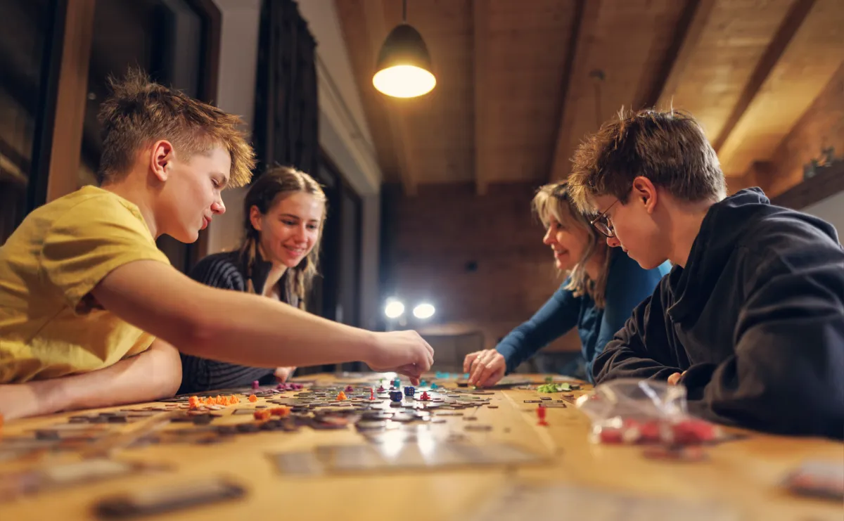 Four young people playing a board game together indoors. No screens!