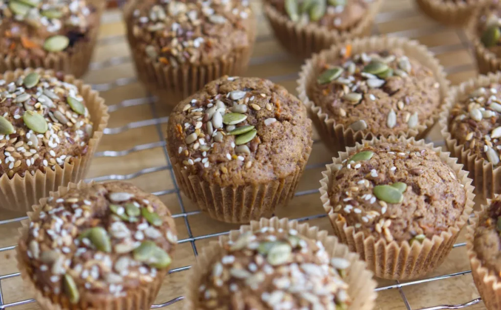 Muffins covered in seeds cooling on a wire rack