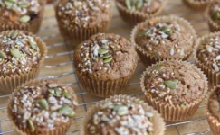 Muffins covered in seeds cooling on a wire rack
