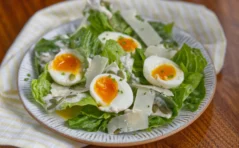 Green cos salad leaves topped with soft boiled eggs and parmesan