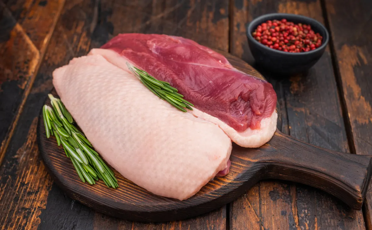 two duck breasts one skin side up, on wooden chopping board