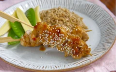 chicken skewers on a white plate, sprinkled with sesame seeds