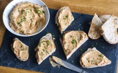 Creamy sardine pate on bread slices with chives on slate board